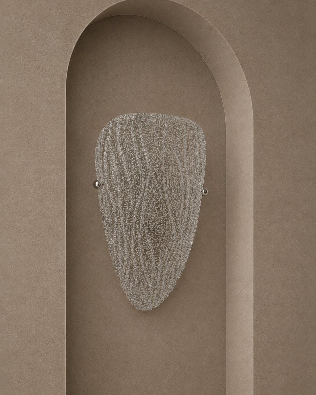 A modern wall sconce with a textured, organic-shaped frosted glass shade and two small silver metal balls on either side, mounted on a warm beige plaster wall with an arched recess.
