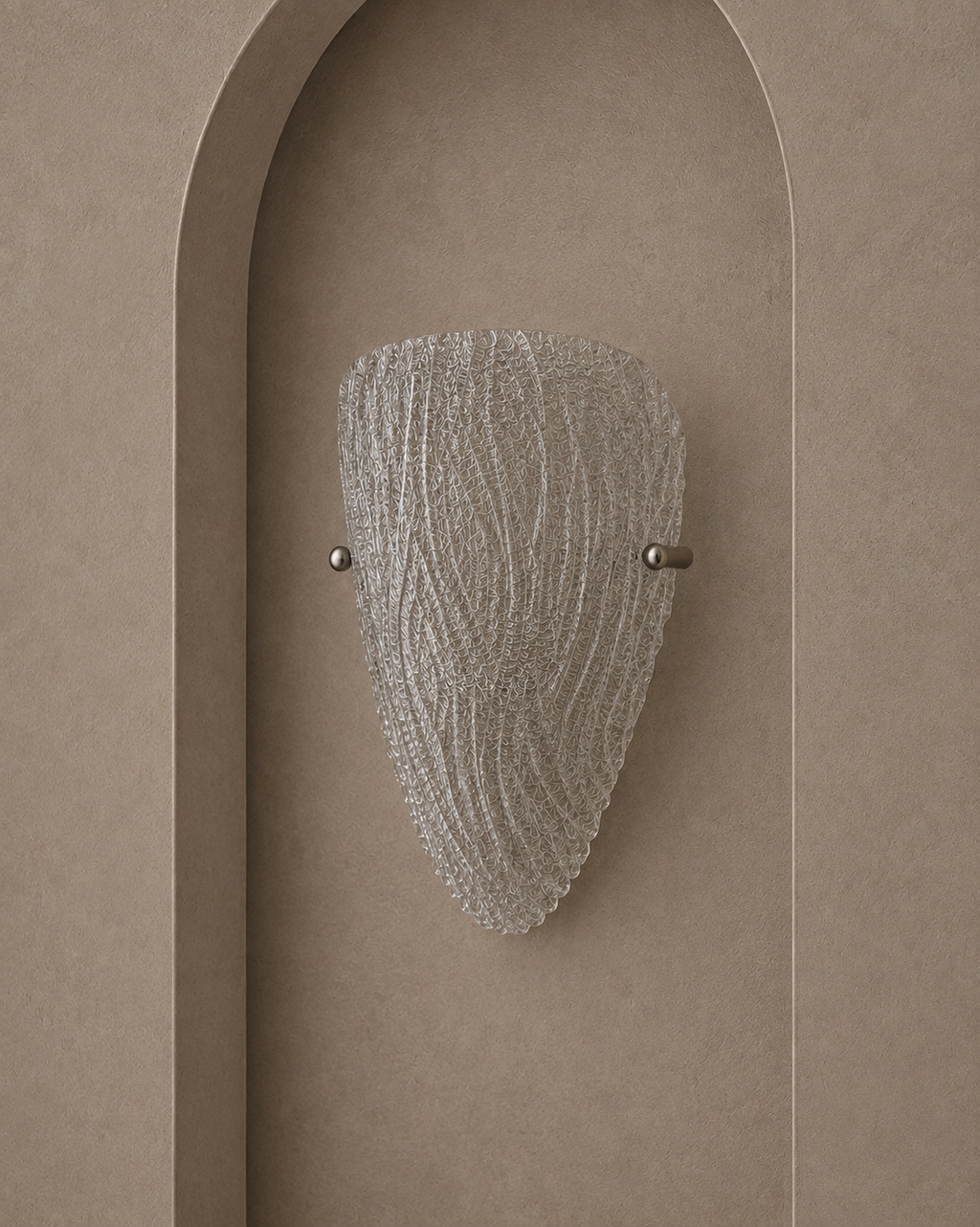 A modern wall sconce with a textured, ribbed clear glass shade and brushed metal hardware, mounted on a warm beige plaster wall with an arched recess.