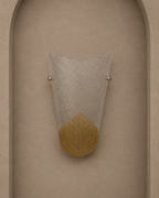 A modern wall sconce with a textured clear glass shade and a gold textured lower section, mounted on a beige stucco wall with an arched recess.
