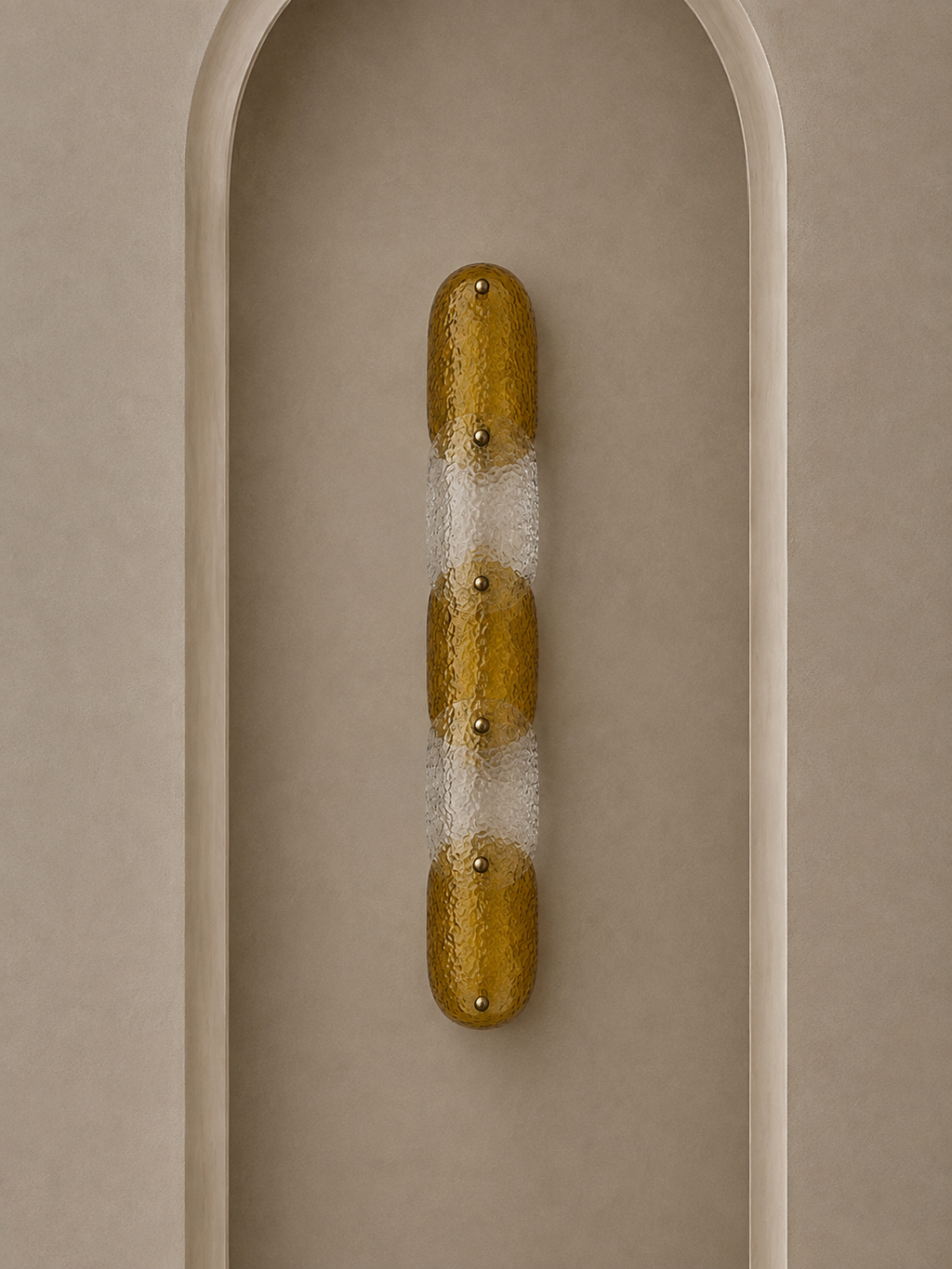 A modern wall sconce with a vertical elongated oval shape, featuring textured metallic gold and frosted white sections, mounted on a beige arched wall.