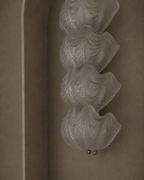 A sculptural wall sconce with four stacked, wavy translucent glass petals and two small gold finials, mounted on a warm taupe plaster wall in a recessed niche.