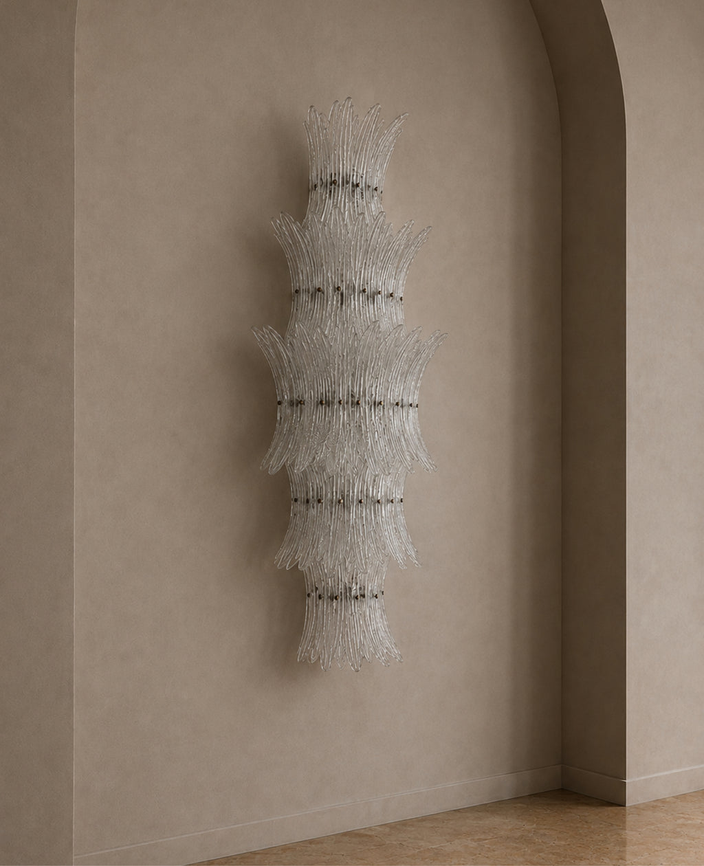 A sculptural wall-mounted chandelier made of layered, fan-like clusters of clear glass rods, suspended in a minimalist interior with beige plaster walls and a tiled floor.