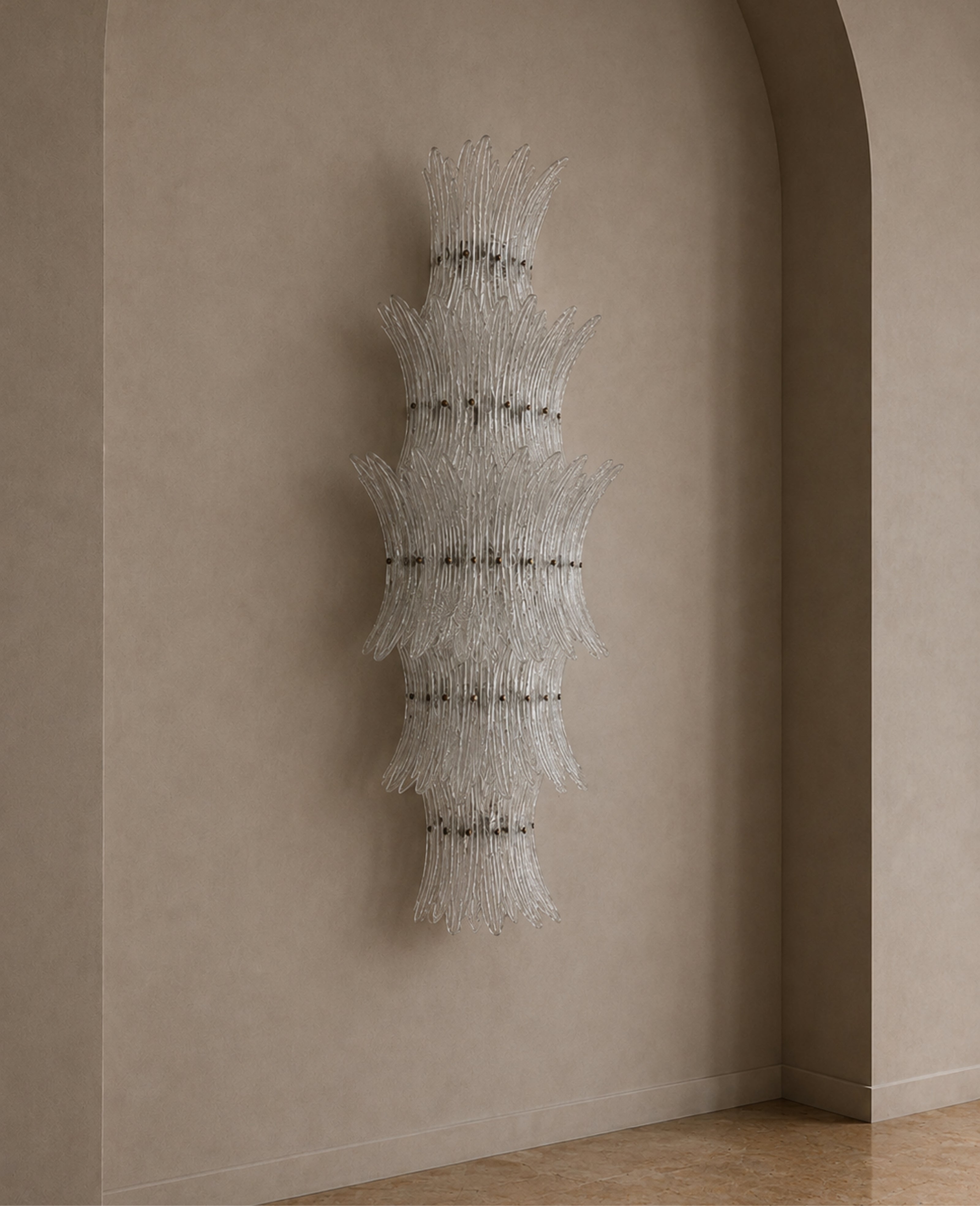 A sculptural wall-mounted chandelier made of layered, fan-like clusters of clear glass rods, suspended in a minimalist interior with beige plaster walls and a tiled floor.
