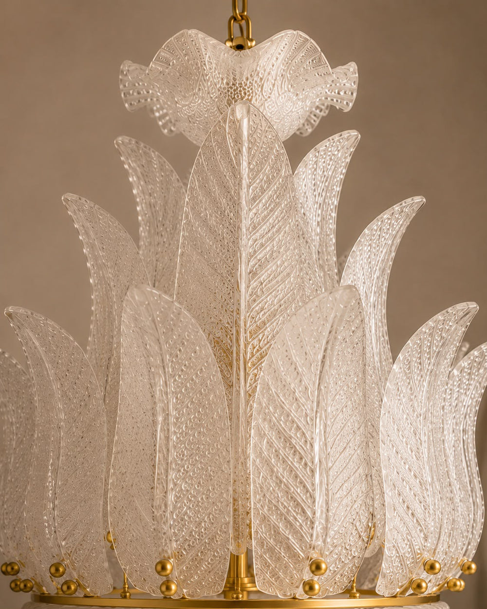 A close-up of a decorative chandelier with multiple translucent textured glass leaf-like shades arranged in a tiered circular structure, with gold metal accents and a hanging chain visible at the top.