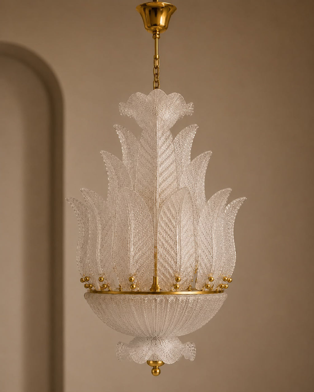 An elegant Italian Murano-style glass chandelier with intricate white textured glass leaves and gold brass hardware, suspended against a warm beige wall.