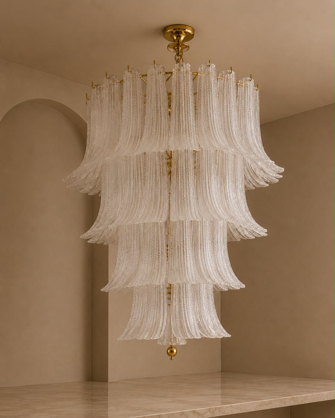 A tiered chandelier with cascading translucent white glass fluted rings and gold-toned metal hardware, hanging in a warm beige interior room.