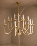 A multi-arm chandelier with curved cream-colored arms and gold-toned hardware, suspended from a matching ceiling canopy in a warm beige interior room.