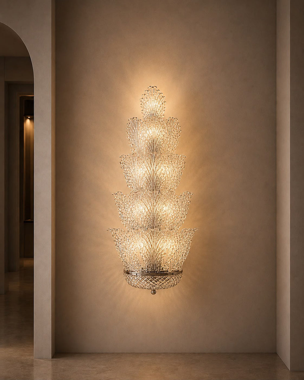 A tiered crystal chandelier wall sconce with a warm glowing light, mounted on a textured beige plaster wall in an elegant interior hallway.