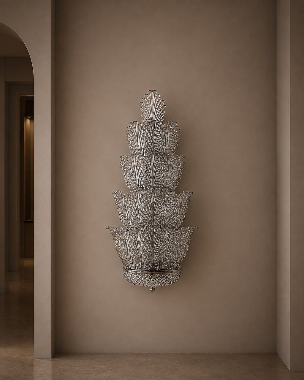 A tiered, lotus-shaped wall sconce with a textured silver mesh pattern, mounted on a warm beige plaster wall in an elegant interior hallway.