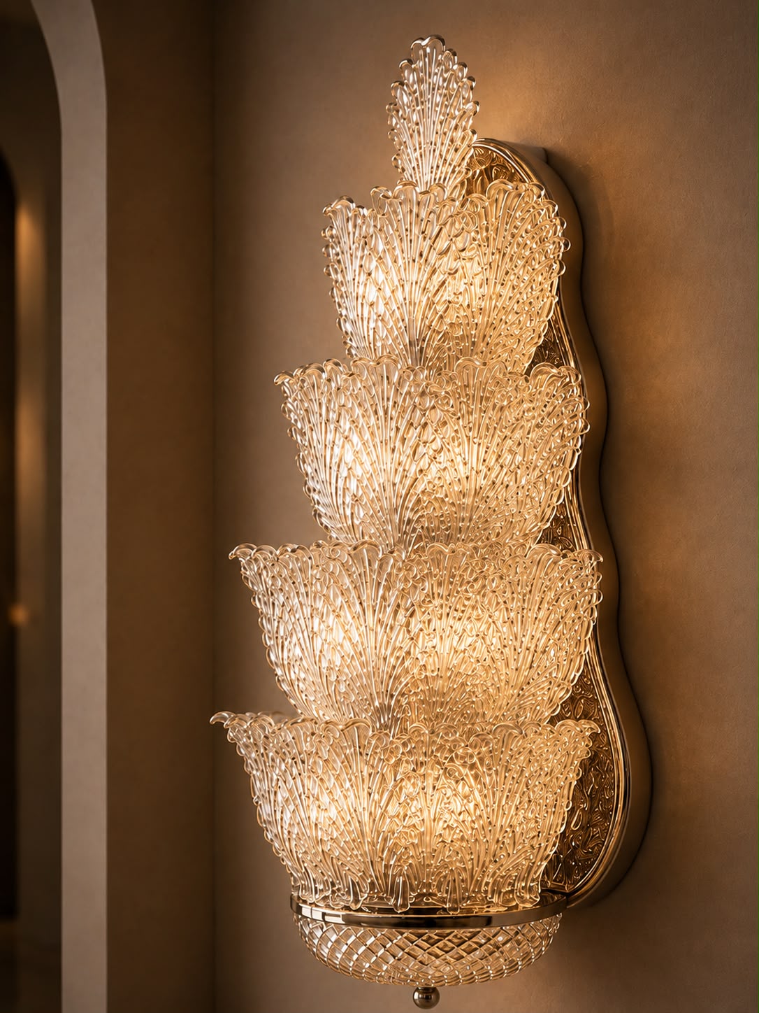 A tiered crystal wall sconce with a warm gold-toned metal frame, mounted on a beige wall.