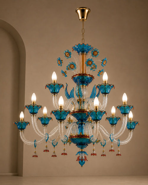 A multi-tiered chandelier with blue glass flower petals, clear crystal arms, and gold-toned metal hardware, shown hanging against a beige wall.