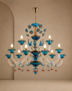 An ornate multi-tier chandelier with vibrant blue glass cups, gold-toned metal arms, and clear crystal strands, shown hanging against a warm beige wall.