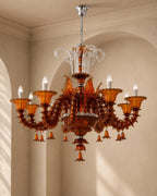 An ornate multi-arm chandelier with amber glass candle-style shades and clear crystal accents, hanging in a beige arched interior room.